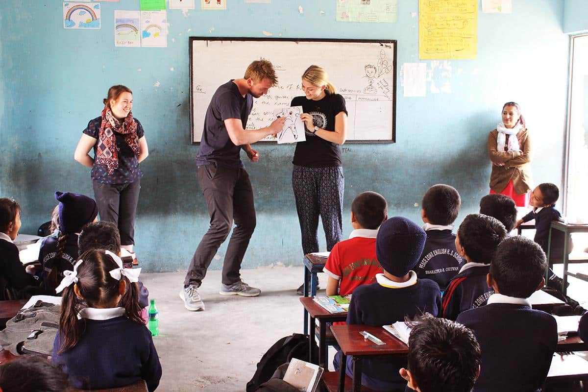 Two volunteers teaching a hygiene class to students in Nepal.